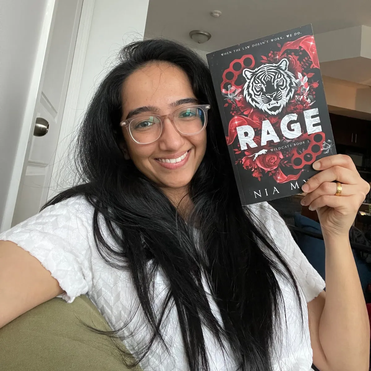 Nia Myst smiling and holding a paperback copy of RAGE
